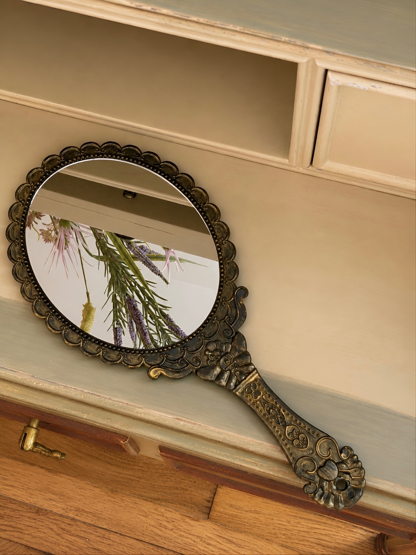 Antique hand mirror resting on the vintage writing desk
