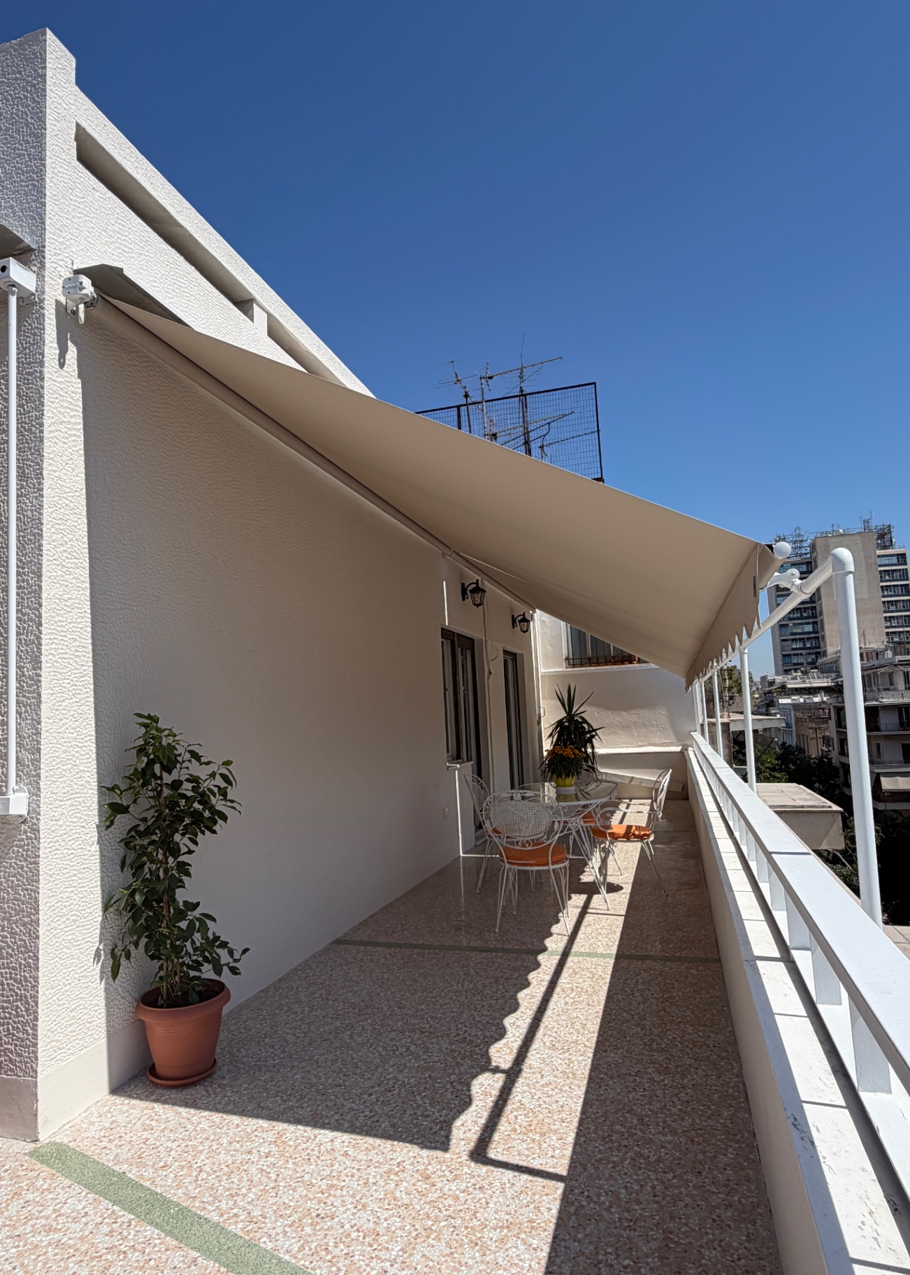 Wide terrace view under the awning with wrought-iron dining set