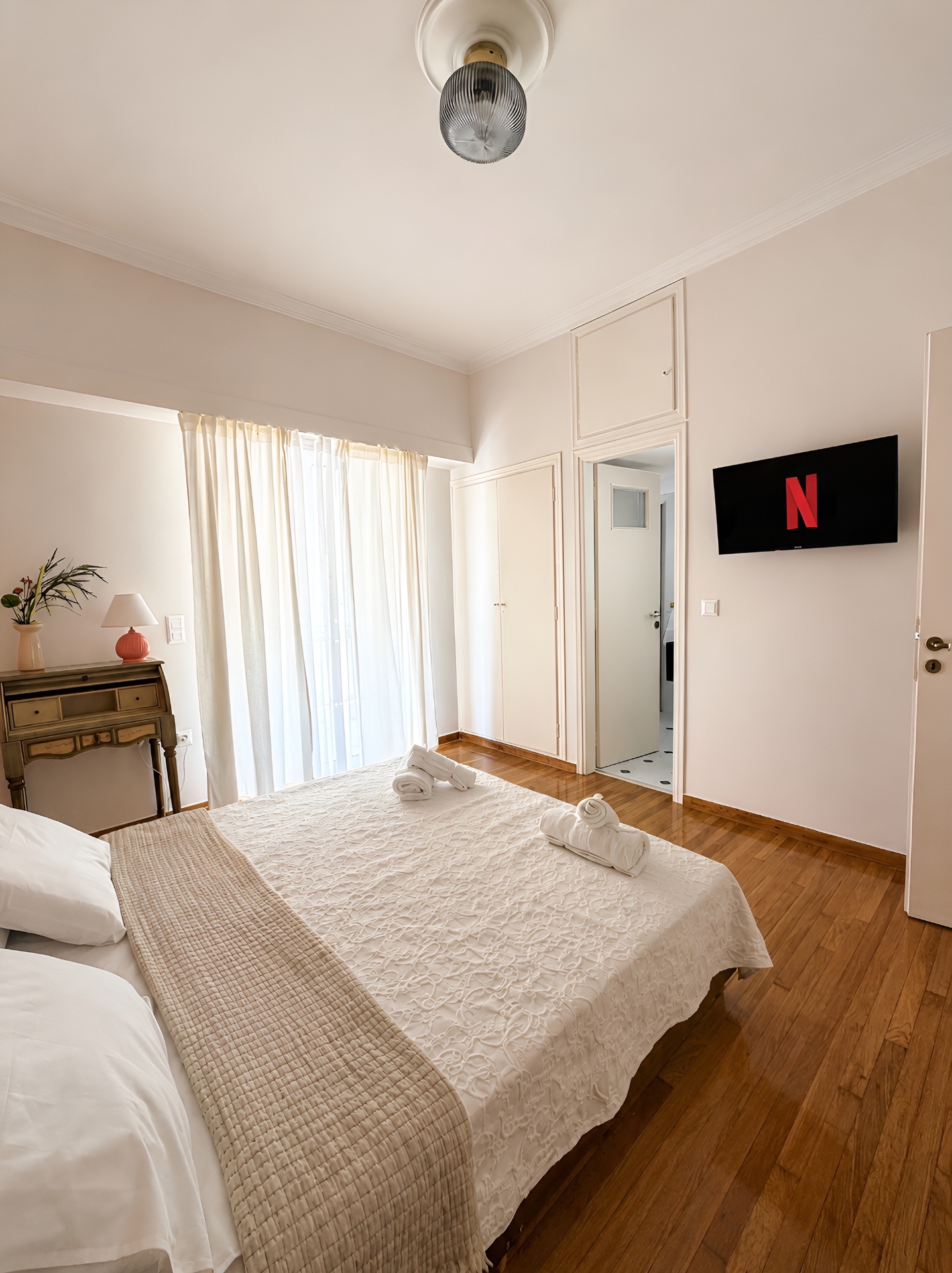 Bedroom view toward the ensuite with tall ceiling and warm timber floor