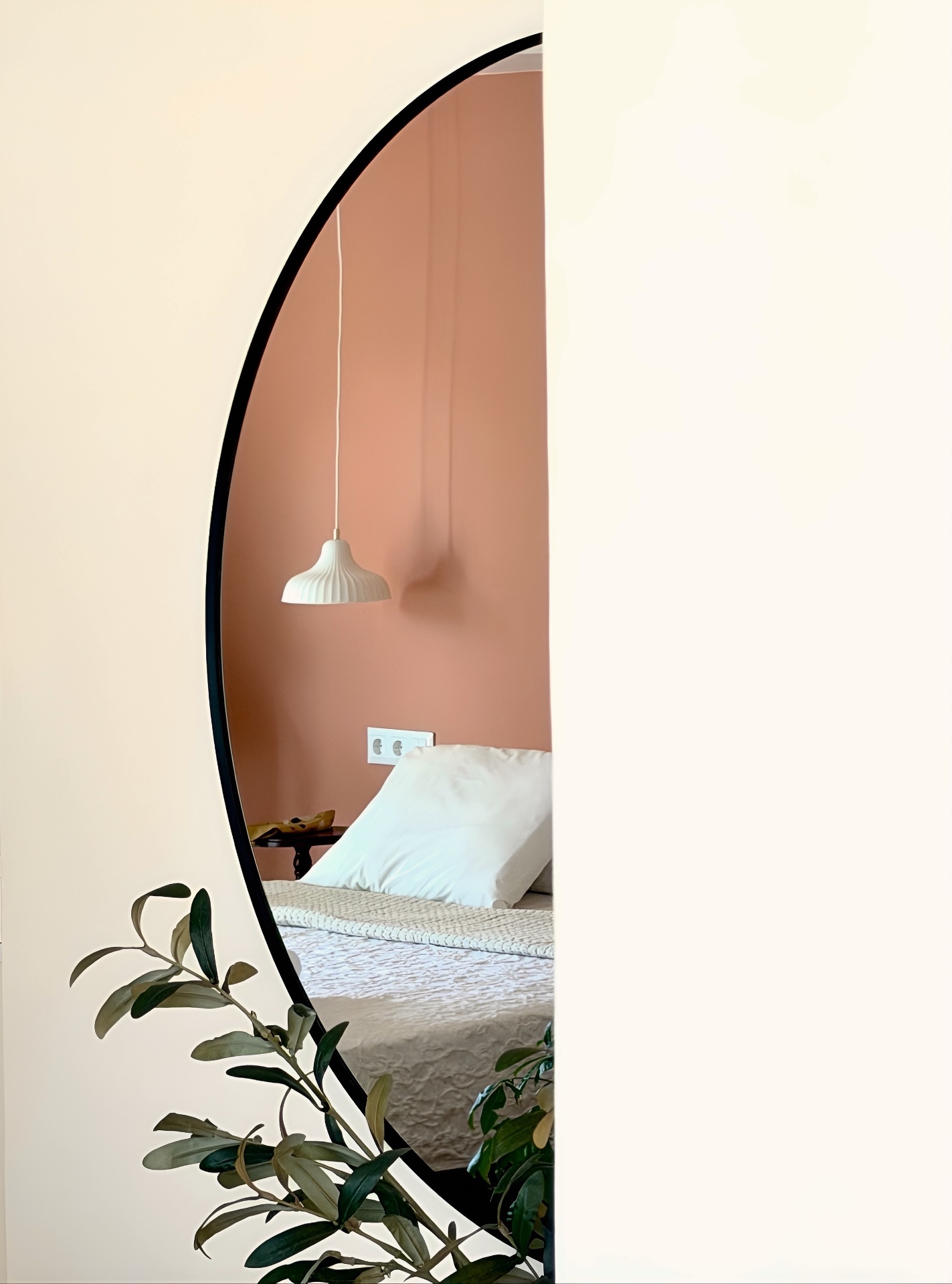 Mirror reflection of the bedroom with sculptural pendant and olive branch