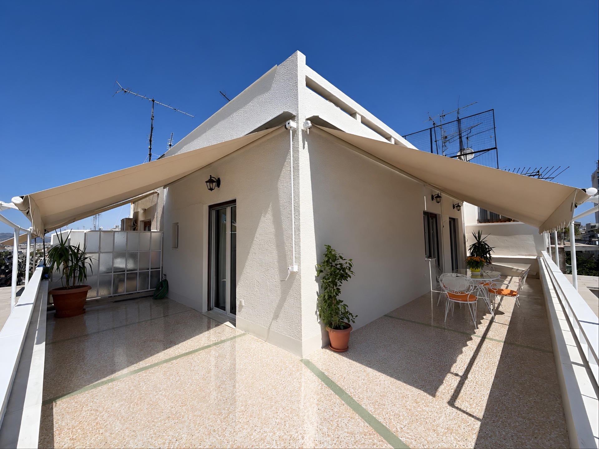 Wraparound rooftop terrace with twin awnings and bright midday light