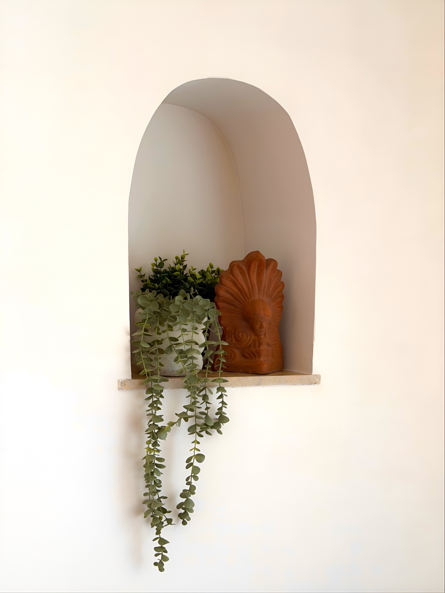 Arched alcove with terracotta sculpture and cascading eucalyptus