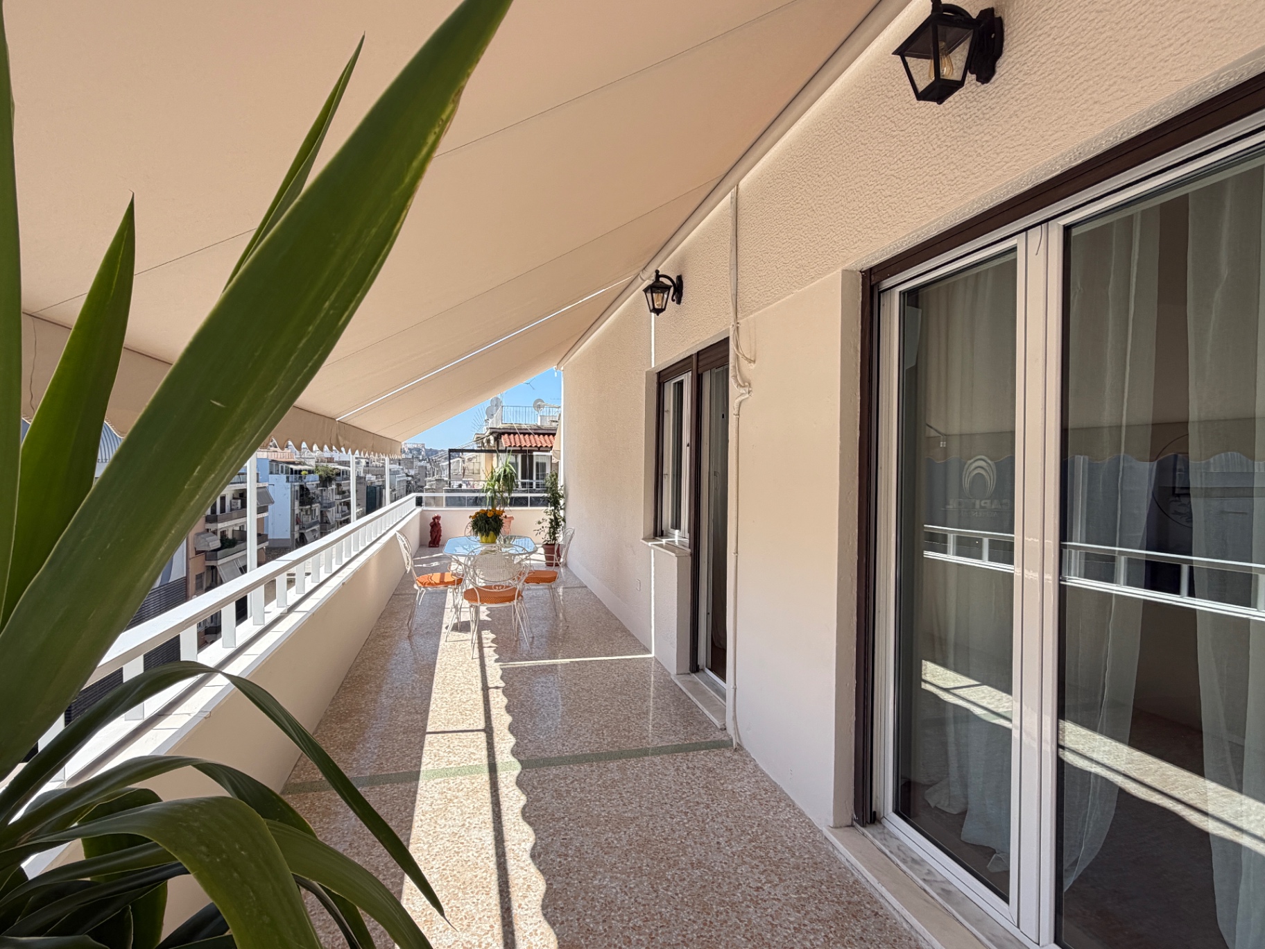 Long shaded balcony lined with glass doors and terrace seating