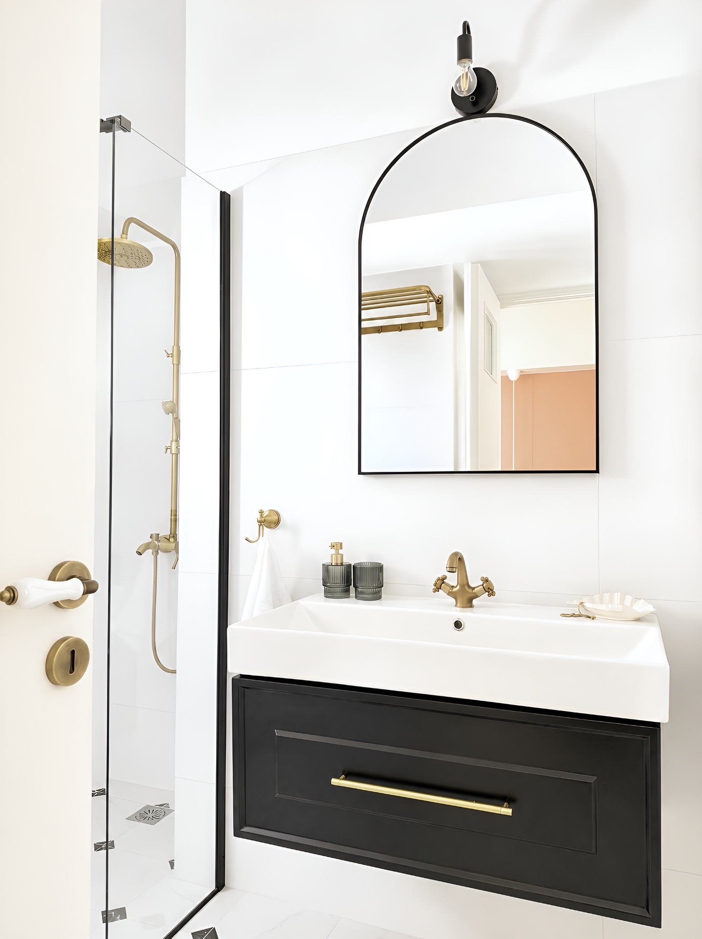 Black vanity with brass cross-handle tap and arched mirror
